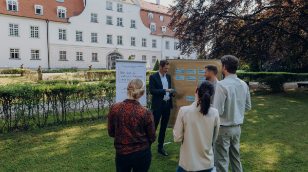 Kleine Seminargruppe im Schlosspark mit Schloss im Hintergrund